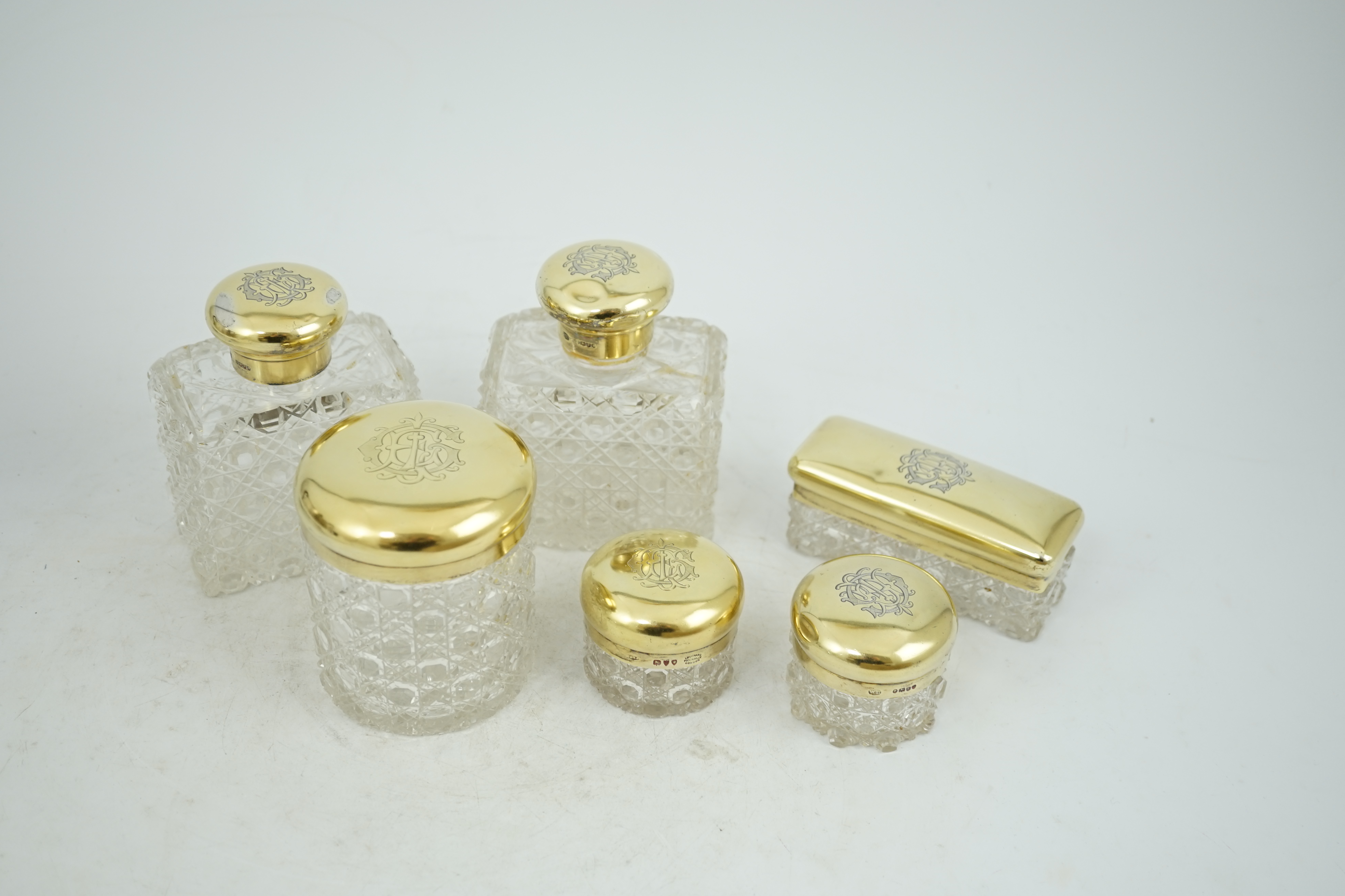 A matched suite of six late Victorian silver gilt mounted cut glass toilet jars two by Charles & George Asprey, London, 1893, tallest 12.2cm.